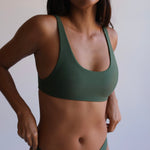 Woman wearing a green bikini against a plain background