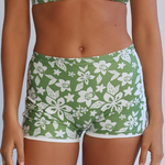 Person wearing a green and white floral bikini set against a plain background