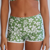 Person wearing a green and white floral bikini set against a plain background