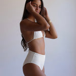 Woman wearing a white bikini against a plain background