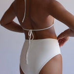 Person wearing a white bikini against a plain background