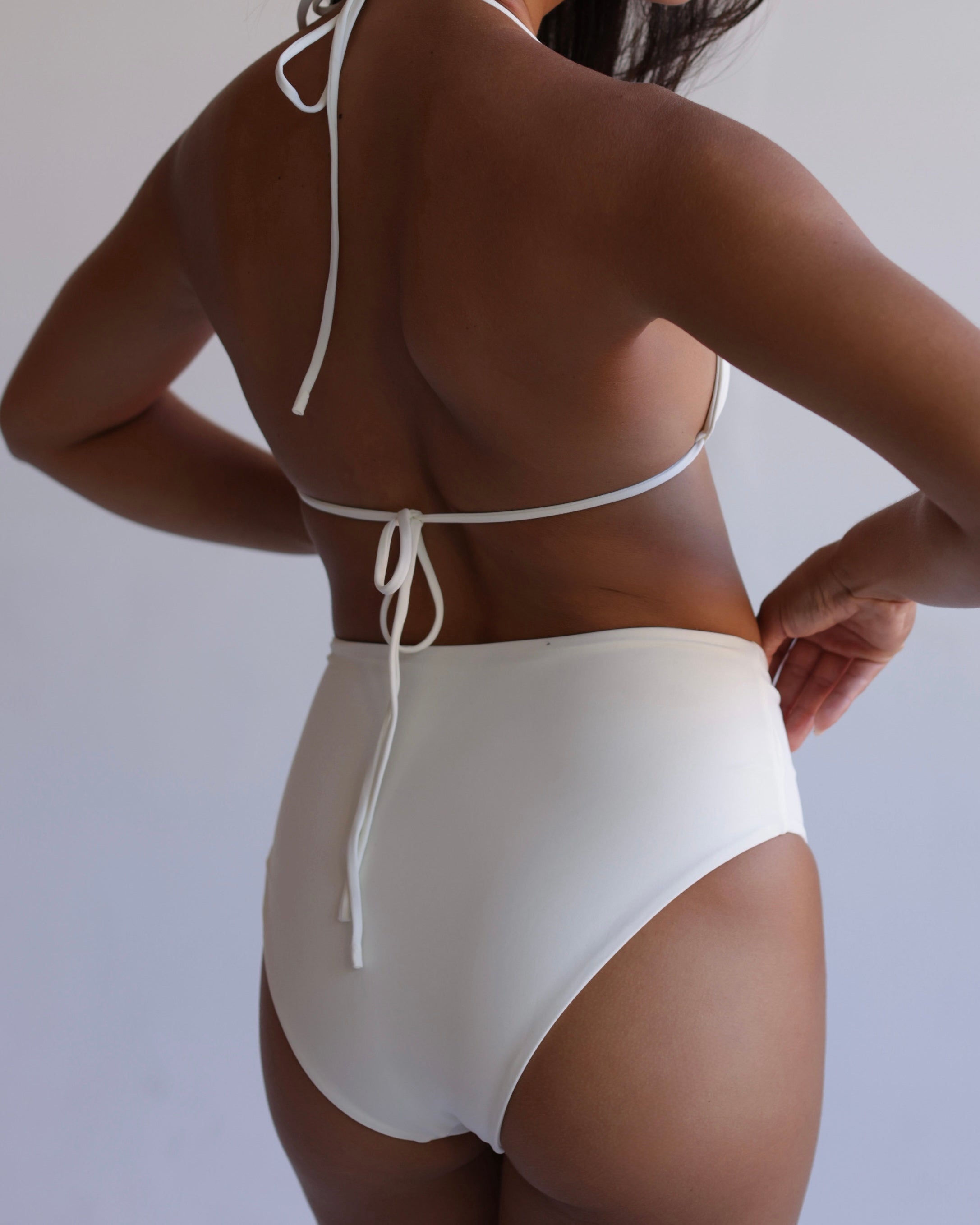 Person wearing a white bikini against a plain background