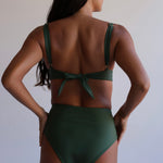Woman wearing a green bikini against a plain background