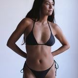 Woman wearing a black bikini against a plain background